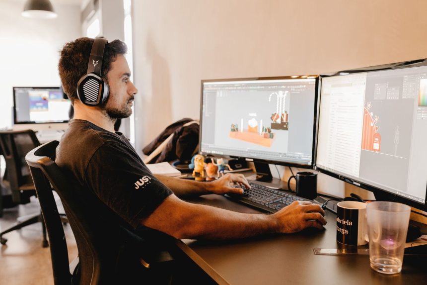 Profissional usando fones de ouvido e trabalhando em um computador com dois monitores em um escritório moderno