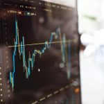 Gráficos de mercado e dados financeiros exibidos em uma tela de computador.